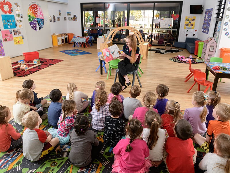 Learn & Play Kindergarten staff reading to big group of children